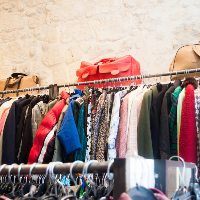 A rack of clothes and handbags in a store.